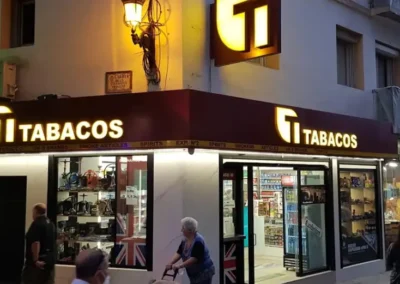 Fachada de Estanco Benidorm Centro iluminada durante la noche, destacando escaparates y logotipo.