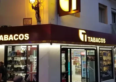 Fachada de Estanco Benidorm Centro iluminada durante la noche, destacando escaparates y logotipo.